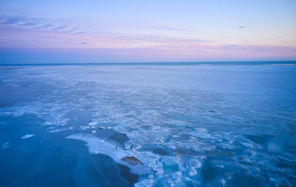 凍結した海の上に夕日の空中ビュー 夕暮れ時の海岸の冬の風景 地平線と日の出に海の氷の融解の上からの眺め 地球温暖化 鮮やかなカラフルなスカイラインの風景 ストック写真