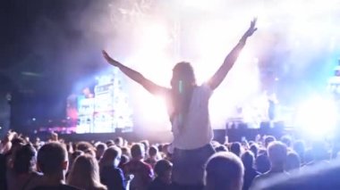 2019-08-09 - Mariupol, Ukraine. MFest festival. Woman sits on boyfriend shoulders, dance waving hands at music concert on open air fest. Crowd jump, applause, enjoy favourite band performance on stage