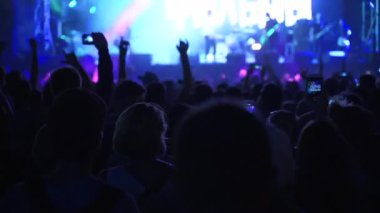 2019-08-09 - Mariupol, Ukrayna. MFest festivali. Siluetler dans ediyor, el sallıyor, fotoğraf çekiyor, canlı müzik konserinin videolarını açık hava festivalinde akıllı telefonlarla kaydediyor. Parlak sahne ışığı