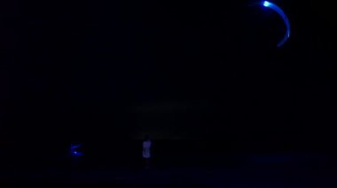 2020-07-25 - Henychensk, Ukraine. Person rides on illuminated kiteboard in the sea with glowing kite at night. Man surfing on a kitesurf with lit parachute on ocean waves in the dark. Extreme sport.