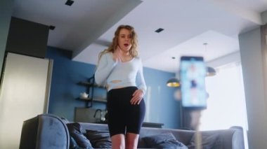 Sosyal medya platformunda beğeniler ve takipçiler için moda dans yarışmasının bayan video kaydı. Komik dans eden bir kadın, bir stüdyoda akıllı telefon kamerasıyla kendi performansını filme alıyor..