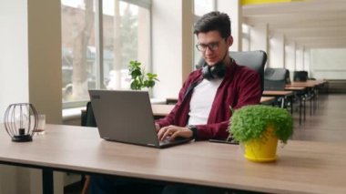 Laptop klavyesinde yazı yazan serbest yazar birlikte çalışma masasında oturuyor. Kamera geliştiricinin etrafında uçuyor ve ofiste bilgisayar ekranında program kodları yazıyor. Çevrimiçi uygulama üzerinde çalışan programcı