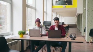 İki hippi iş arkadaşı geniş uzay ofisinde dizüstü bilgisayarlarla oturma projesini paylaşıyor. Geliştirici yazılım program kodunu tartışır. Tasarımcı ve yönetici bir çalışma planına danışmanlık yapıyor.