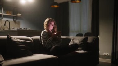 Akıllı telefonları kaydıran, internette sörf yapan gece şık oturma odasındaki kanepede oturan bir kadın. Mobil oyunlar oynayan ya da mağazadan alışveriş yapan bir kadın. Telefonu olan kız sosyal ağlarda sohbet etmekten hoşlanıyor.