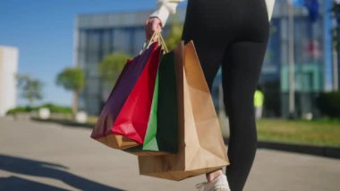 Alışveriş merkezinden alışveriş torbalarıyla gezen bir kadının yakın çekimi. Kara Cuma satışından mal alan bir kızın düşük açılı görüntüsü. Kese kâğıdı dolu bir kadın. Yavaş çekim geri görünümü.