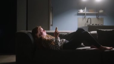 Akıllı telefonları kaydıran, internette sörf yapan gece şık oturma odasındaki kanepede uzanan bir kadın. Mobil oyunlar oynayan ya da mağazadan alışveriş yapan bir kadın. Telefonu olan kız sosyal ağlarda sohbet etmekten hoşlanıyor.