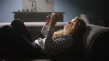 Akıllı telefonları kaydıran, internette sörf yapan gece şık oturma odasındaki kanepede uzanan bir kadın. Mobil oyunlar oynayan ya da mağazadan alışveriş yapan bir kadın. Telefonu olan kız sosyal ağlarda sohbet etmekten hoşlanıyor.