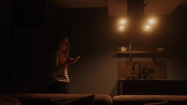 Kadın, oturma odasındaki yıldırım senaryolarını kontrol etmek ve şarap dökmek için telefonda uygulama kullanıyor. Kadın mutfağa giriyor, akıllı ev bilgisayarındaki akıllı telefon uygulaması ile ışıkları açıyor. Nesnelerin interneti
