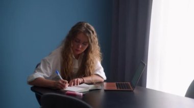 Bilgisayarda uzaktan öğrenme dersinde online ders izleyen kız öğrenci. Çalışan bir kadın, not defterine notlar yazan, web dersi dinleyen bir kadın. Evde ödev yapan bir kız. Takımla uzak çalışma.
