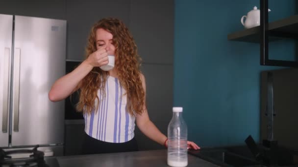 女人喝过期的牛奶 站在厨房里肚子痛 患有乳糖耐受症的女性尝试低质量的牛奶 有消化不良问题的女孩肚子痛 — 图库视频影像