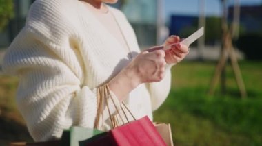 Kadın alışveriş çantasından kağıt makbuz alıyor, yüksek fiyatlara göre harcamaları hesaplıyor, enflasyon artışını hesaplıyor. Alışverişci kızarıklıktan gelen masrafları sayıyor. Kara Cuma satışından alınan dürtüler. Tüketim.