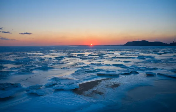 凍結した海の上に夕日の空中ビュー 夕暮れ時の海岸の冬の風景 地平線と日の出に海の氷の融解の上からの眺め 地球温暖化 鮮やかなカラフルなスカイラインの風景 — ストック写真