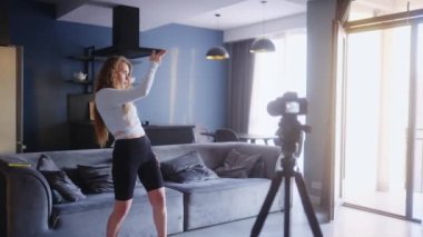 Popüler kız, sosyal medya platformunda beğeniler ve takipçiler için moda dans yarışması videosu kaydediyor. Komik dans eden bir kadın, ev stüdyosundaki oturma odasında gösterisini kameraya çekiyor..