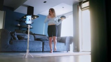 Sosyal medya platformunda beğeniler ve takipçiler için moda dans yarışması videosu kaydeden neşeli kız. Komik dans eden bir kadın, bir stüdyoda akıllı telefon kamerasıyla kendi performansını filme alıyor.
