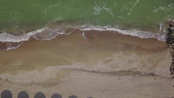ビーチでのわら傘の空中ビュー 海の波砂の海岸を洗う 豪華な熱帯リゾートの静かな海岸線 上から下に向かってドローンが上昇 — ストック動画