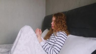 Üşütmüş, öksüren ve burnunu sümküren boğazı, ateşi ve baş ağrısı olan bir kadın. Genç beyaz kadın koronavirüsten muzdarip. Covid19. İzolasyon alnına dokunurken.