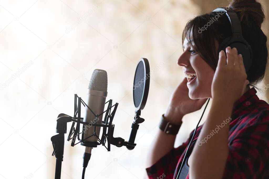 Professional singer woman recording a song in a studio