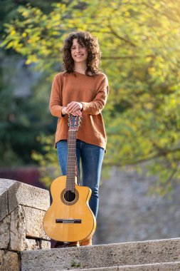 Kız kameranın önünde İspanyol gitarıyla poz veriyor.