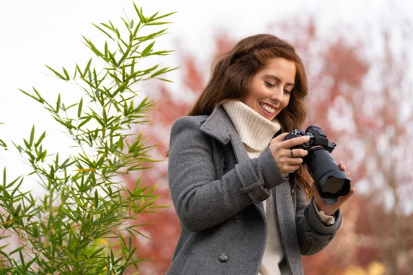 Wanita muda melihat kamera fotonya dan tersenyum di taman — Stok Foto