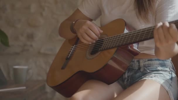 Close-up van een zingende vrouw die Spaanse gitaar speelt naast een raam in een kamer — Stockvideo