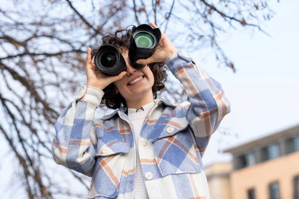 Jong brunette krullend haar vrouw rommelen rond met twee fotografie lenzen — Stockfoto