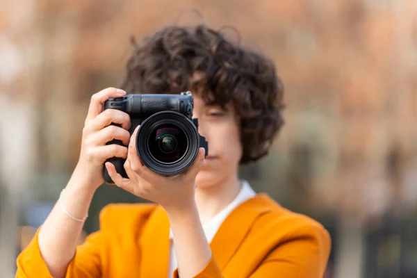 Young brunette woman with curly hair taking a picture with her big camera — 图库照片