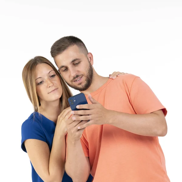 Um jovem casal em um fundo branco olhando para o smartphone azul. — Fotografia de Stock