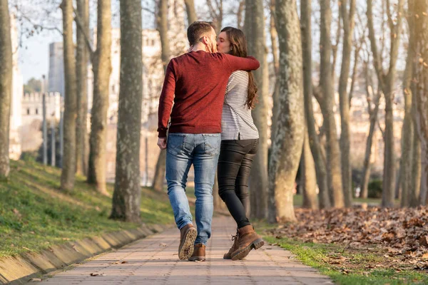 Молодой человек и женщина пара прогуливаются и целуются в парке на День Святого Валентина — стоковое фото