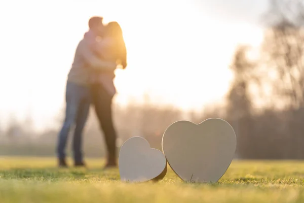 Młoda para całuje się za dwoma kształtami serca w parku w Walentynki — Zdjęcie stockowe