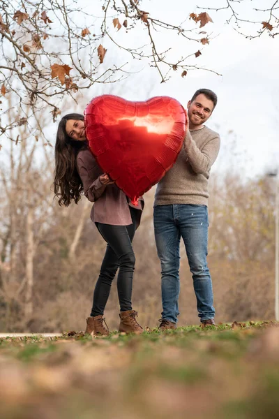 Młoda para świętuje walentynki trzymając balon w kształcie serca — Zdjęcie stockowe