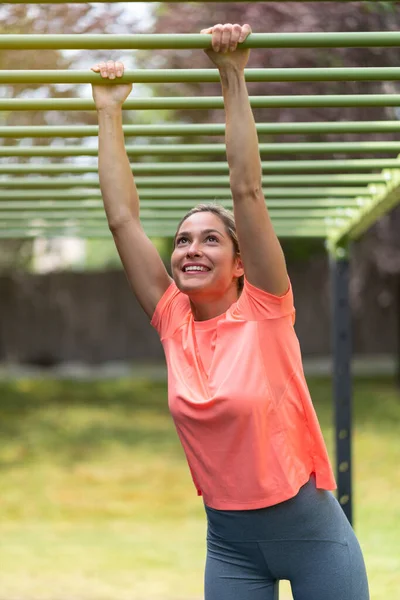 Mujer rubia fuerte en un gimnasio al aire libre haciendo ejercicio en una jaula de estructura —  Fotos de Stock