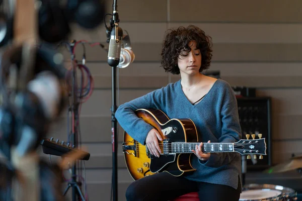 Genç bir şarkıcı kadın gitarıyla berbat bir stüdyoda şarkı kaydediyor.