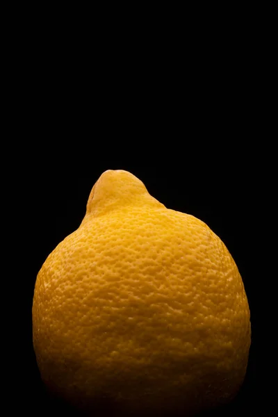 Fotografía macro de un limón amarillo sobre un fondo negro — Foto de Stock