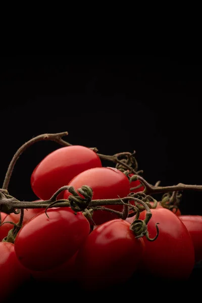 Fotografía macro de un ramo de tomates cherry sobre un fondo negro — Foto de Stock