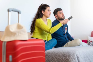 Genç turist çift otel odasında televizyon seyrediyor.