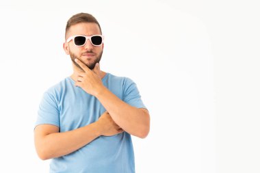 Beyaz arka planda güneş gözlüğü takan genç bir adam.