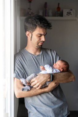 Genç baba, yeni doğmuş bebeğini kollarına alıp, pencerenin kenarına gitti.
