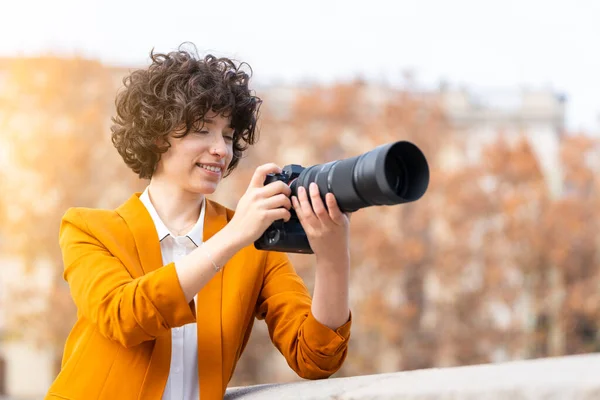 Fiatal barna nő göndör haj csinál egy képet teleobjektívvel — Stock Fotó