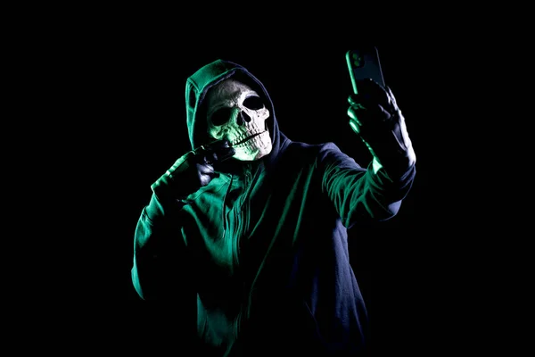 Modern death character on a black background taking a selfie with his phone — Stock Photo, Image