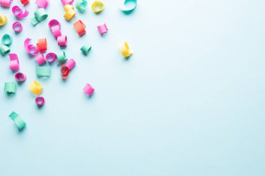 Colorful paper confetti on blue background with copy space.