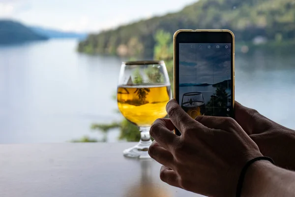 Mobil ve manzaralı bir bardak biranın fotoğrafını çekiyorum.