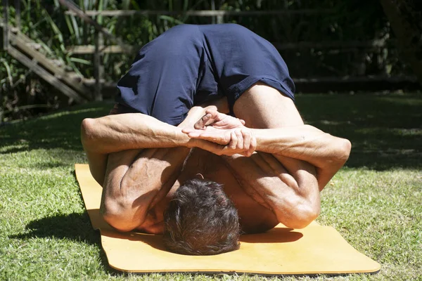yoga outdoor in a relax position, young and flexibility man, with orange yoga mat