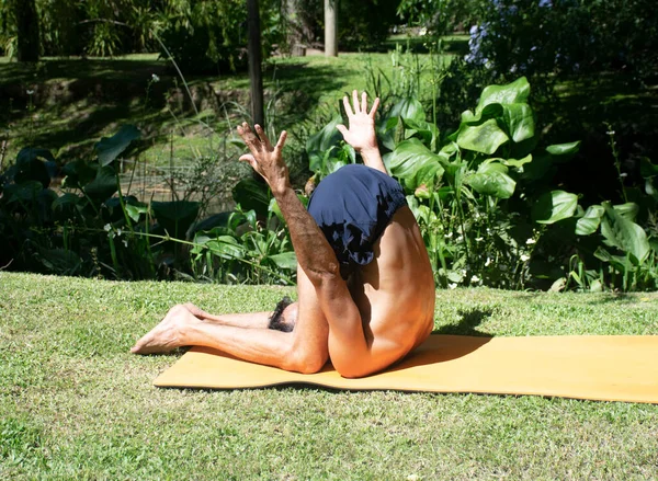 yoga outdoor in a relax position, young and flexibility man, with orange yoga mat
