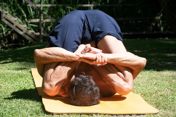 yoga outdoor in a relax position, young and flexibility man, with orange yoga mat