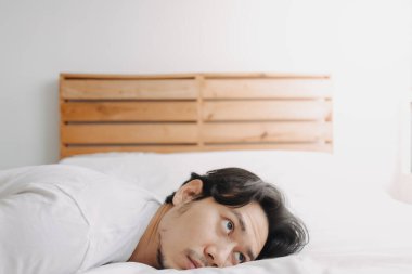 Yorgun bir adam yorgun hissederken yatağa uzandı..