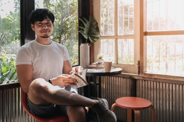 Happy man drink coffee and reading book in warm light of summer.