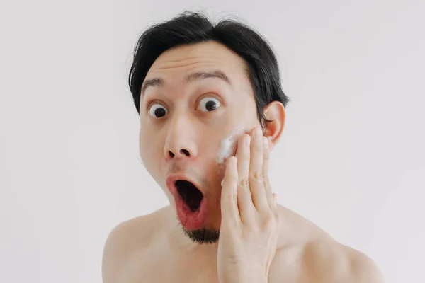 Wow and surprise face of man using skin care product on his face.