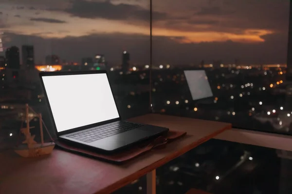 Laptop op het bureau op het balkon met 's avonds zonsondergang uitzicht op de stad. — Stockfoto