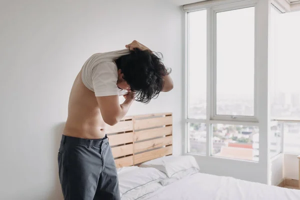 Mann zieht in Schlafzimmerwohnung sein T-Shirt aus. — Stockfoto