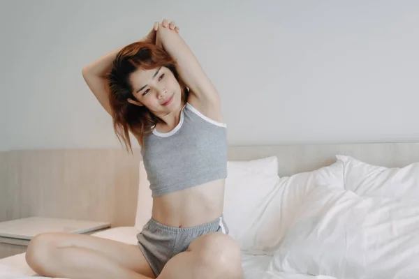 Ελκυστική γυναίκα με εσώρουχα που τεντώνεται στο κρεβάτι το πρωί. — Φωτογραφία Αρχείου